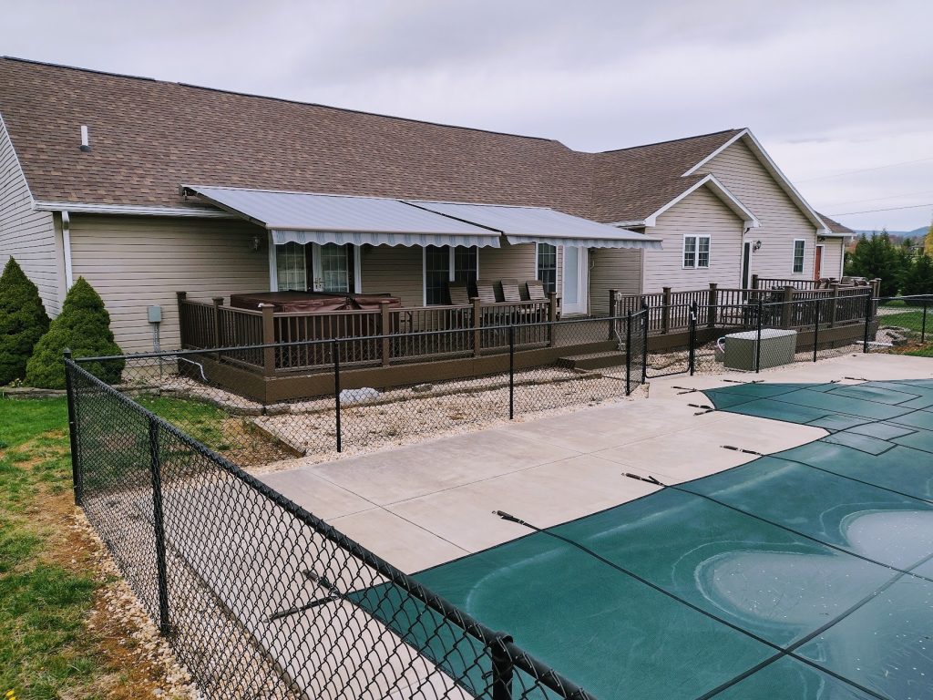 retractable awning over a deck with hot tub next to a pool